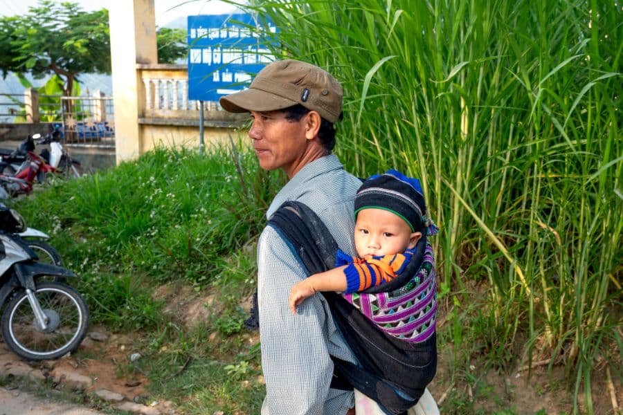En Asie, homme marchant avec enfant en porte-bébé dans le dos
