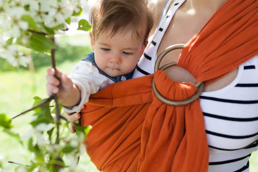 porte-bébé d'appoint : Bébé en écharpe touchant fleurs.
